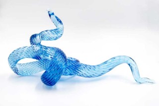 A single rod of translucent and striated marine blue glass is twisted, looped and shaped into an elegant wave by artist John Paul Robinson.