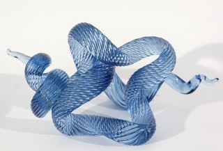 A single rod of translucent and striated marine blue glass is twisted, looped and shaped into an elegant wave by artist John Paul Robinson.