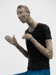 Perched on a silver plinth, a small figure gestures to the viewer in this paper mache sculpture by Paul Duval.