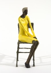 A seated figure in yellow waits quietly in this contemplative paper mache sculpture by Paul Duval.